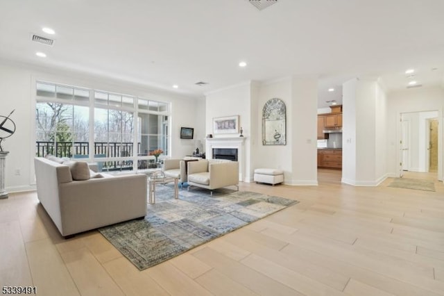 living area with light wood finished floors, visible vents, baseboards, recessed lighting, and a fireplace