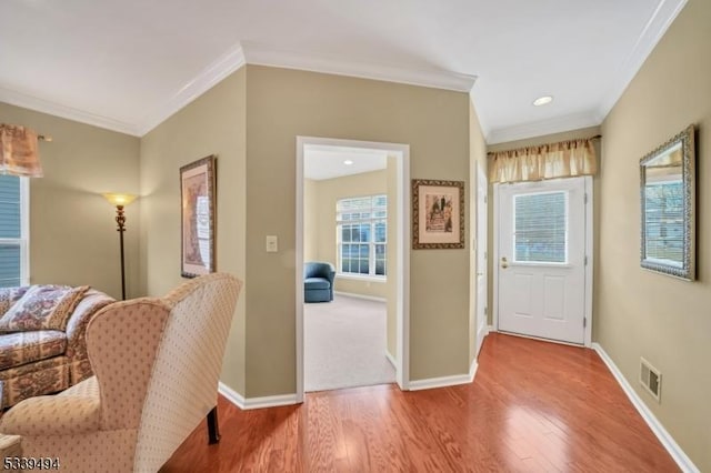 foyer with crown molding, wood finished floors, visible vents, and baseboards