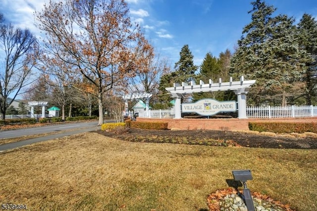 community sign with fence and a yard