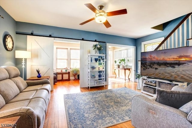 living room featuring a ceiling fan, wood finished floors, and a barn door