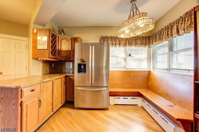 kitchen featuring a baseboard heating unit, brown cabinets, light wood finished floors, stainless steel fridge, and decorative light fixtures