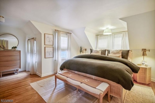 bedroom featuring lofted ceiling, baseboards, and wood finished floors