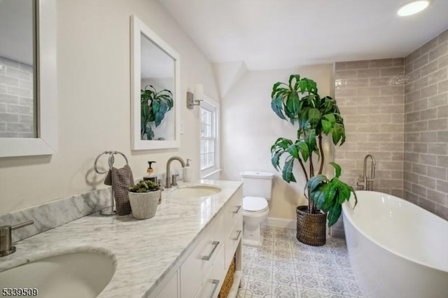 full bathroom featuring double vanity, a freestanding tub, toilet, and a sink