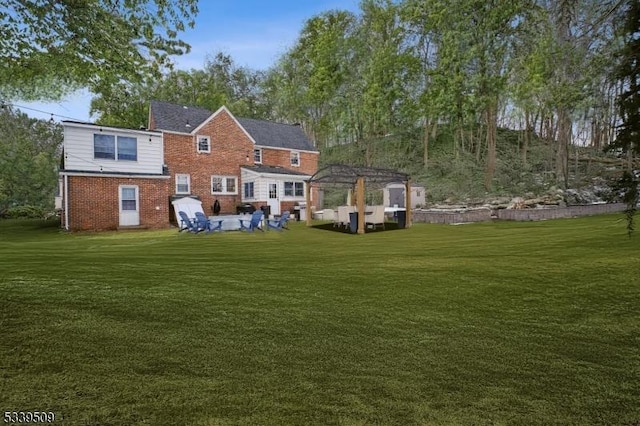 rear view of house featuring brick siding and a yard