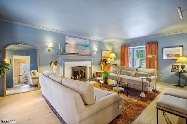 living room with a fireplace with flush hearth, arched walkways, crown molding, and wood finished floors