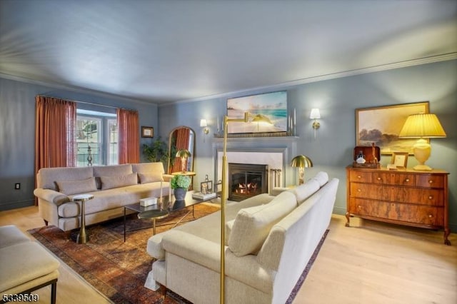 living room featuring a warm lit fireplace, wood finished floors, and crown molding