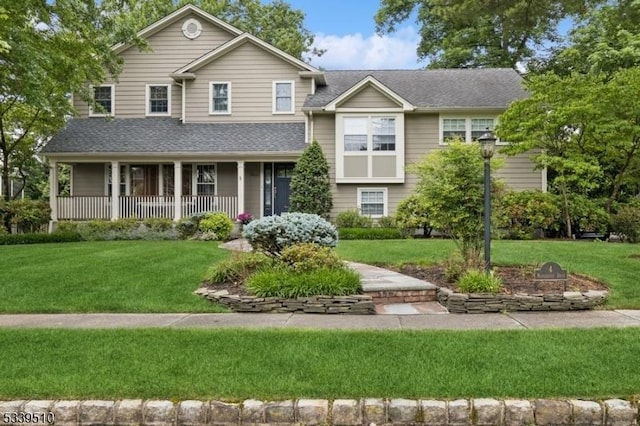 view of front of house featuring a shingled roof, a front lawn, and a porch