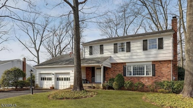 view of front facade with brick siding, a chimney, aphalt driveway, an attached garage, and a front yard