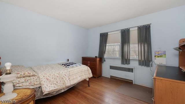 bedroom featuring wood finished floors and radiator