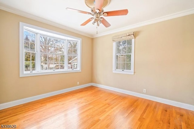 spare room featuring ornamental molding, wood finished floors, a ceiling fan, and baseboards