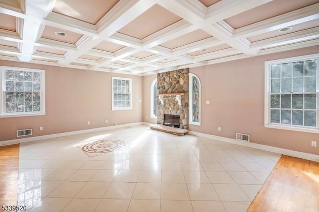 unfurnished living room with a stone fireplace, visible vents, and a healthy amount of sunlight