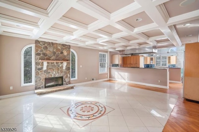 unfurnished living room featuring beamed ceiling, a stone fireplace, baseboards, and light tile patterned floors