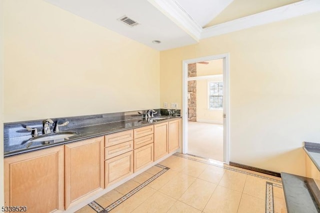 kitchen featuring dark countertops, vaulted ceiling, visible vents, and a sink