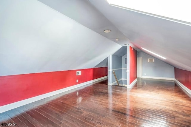 bonus room featuring lofted ceiling, visible vents, baseboards, and dark wood-type flooring