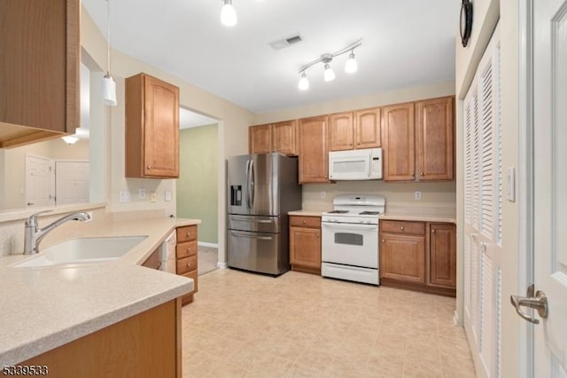 kitchen featuring white appliances, a sink, visible vents, light countertops, and pendant lighting