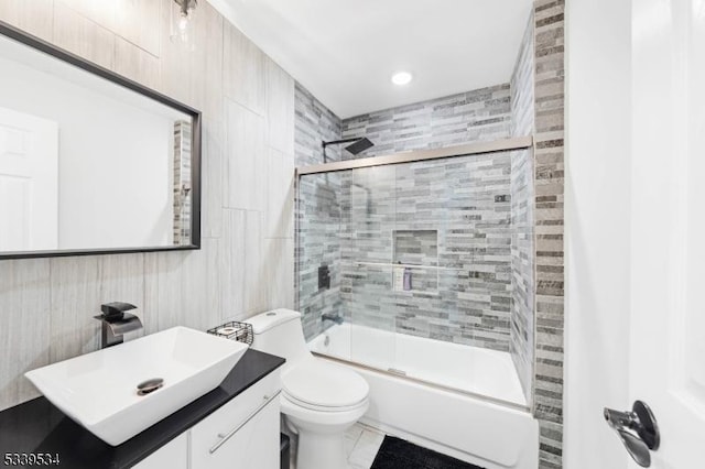 bathroom featuring toilet, enclosed tub / shower combo, and vanity