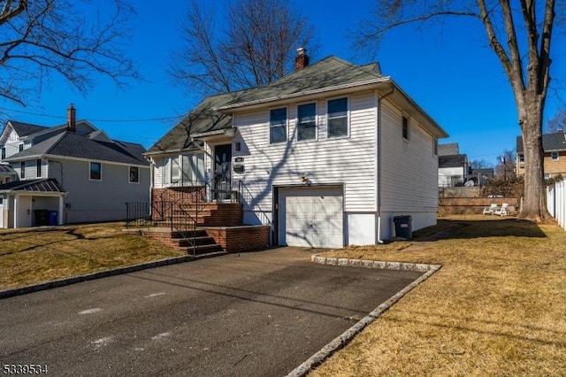 view of front of house featuring a chimney, a front yard, fence, a garage, and driveway