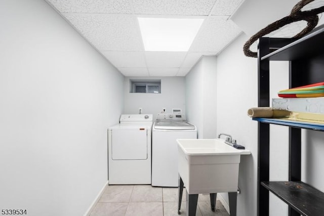 laundry room featuring light tile patterned floors, baseboards, separate washer and dryer, and a sink