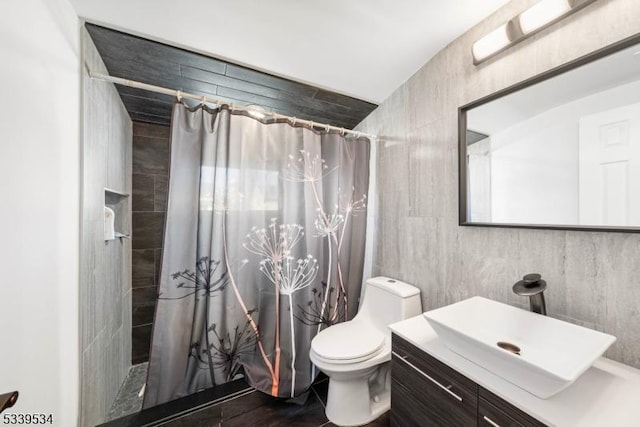 bathroom featuring toilet, tile walls, tiled shower, and vanity