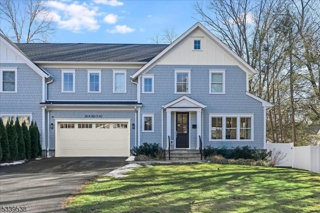 view of front of property with aphalt driveway, an attached garage, fence, board and batten siding, and a front yard