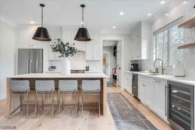 kitchen featuring beverage cooler, stainless steel appliances, and white cabinets