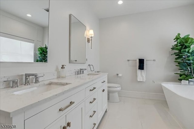 full bath with double vanity, a freestanding tub, baseboards, and a sink