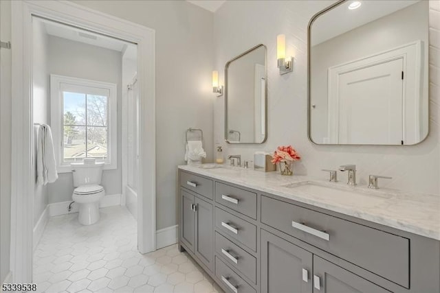 bathroom with double vanity, baseboards, toilet, and a sink