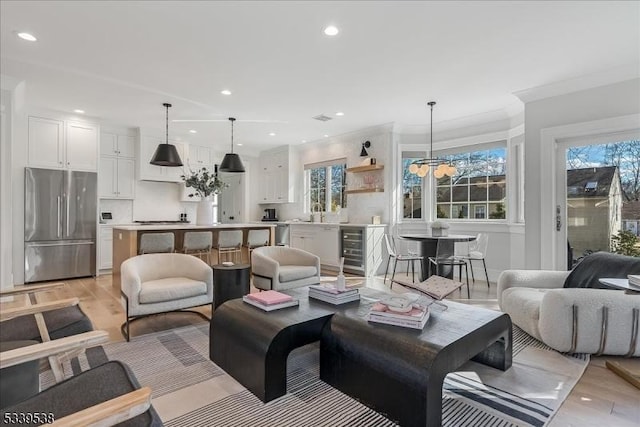 living area featuring beverage cooler, recessed lighting, light wood-style flooring, and a healthy amount of sunlight