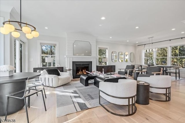 living area featuring a warm lit fireplace, light wood finished floors, and recessed lighting