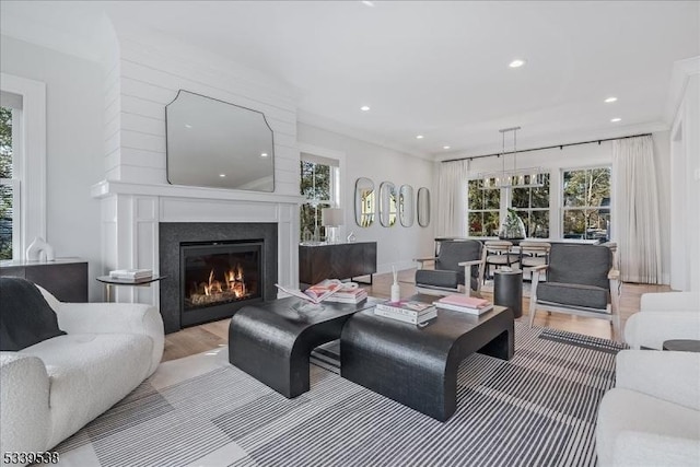 living area featuring recessed lighting, wood finished floors, a wealth of natural light, and a glass covered fireplace