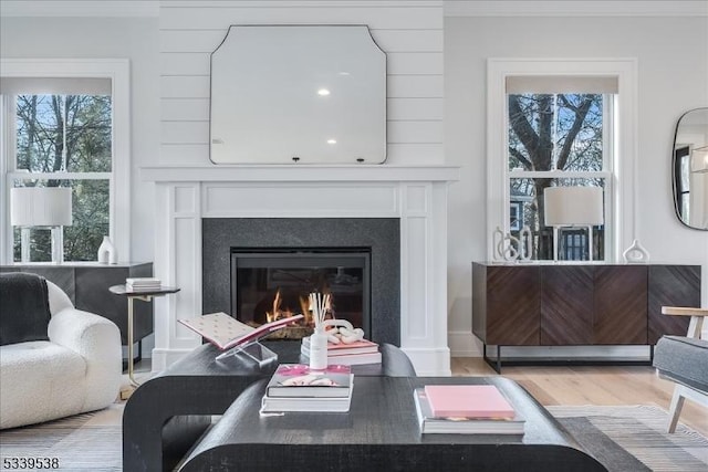 living room with ornamental molding, a wealth of natural light, a glass covered fireplace, and wood finished floors