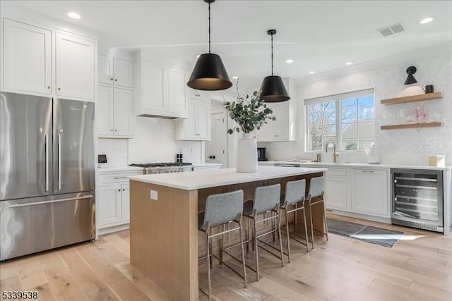 kitchen featuring a kitchen island, wine cooler, appliances with stainless steel finishes, and light wood-style flooring