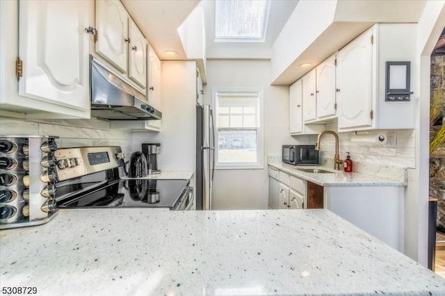 kitchen with stainless steel appliances, white cabinets, and under cabinet range hood