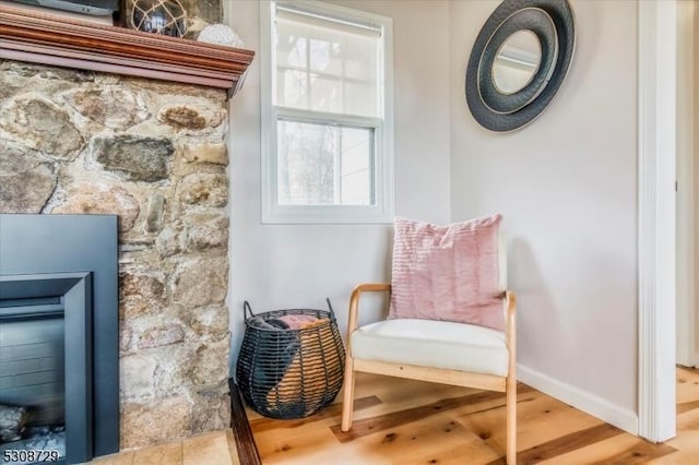 sitting room featuring a fireplace, baseboards, and wood finished floors