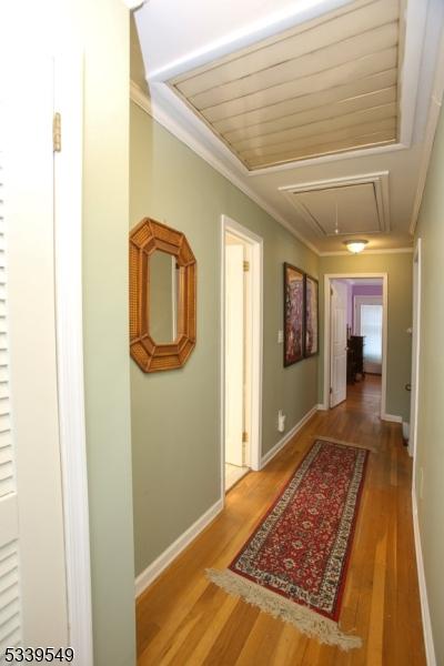 hallway featuring attic access, ornamental molding, baseboards, and wood finished floors