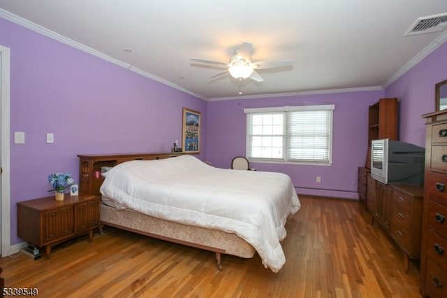 bedroom featuring visible vents, ornamental molding, a ceiling fan, a baseboard heating unit, and wood finished floors