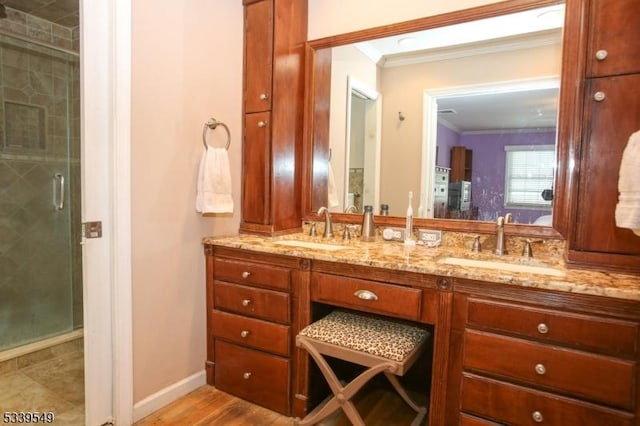 bathroom with double vanity, a shower stall, ornamental molding, and a sink