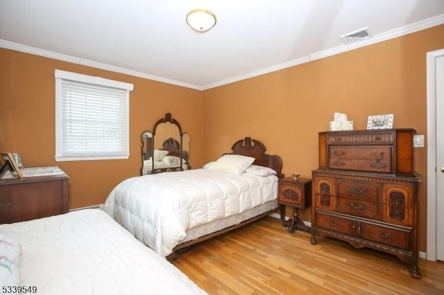 bedroom with visible vents, wood finished floors, and ornamental molding