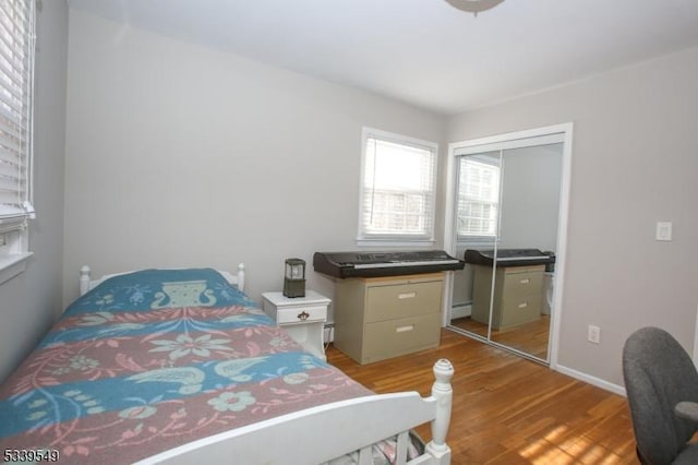 bedroom featuring a baseboard radiator, a closet, and wood finished floors