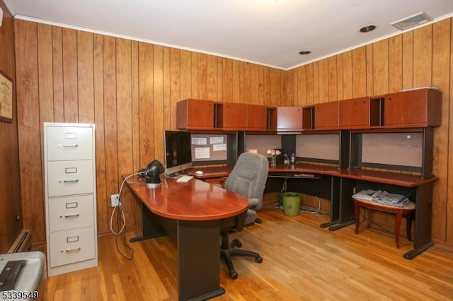 office space with baseboard heating, visible vents, wooden walls, and light wood finished floors