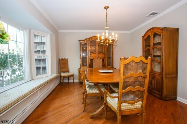 dining room featuring visible vents, wood finished floors, crown molding, a baseboard heating unit, and a notable chandelier