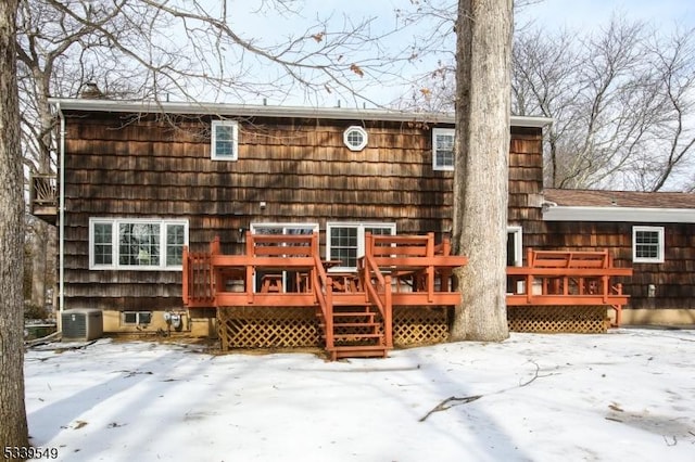 snow covered property with a wooden deck and central air condition unit