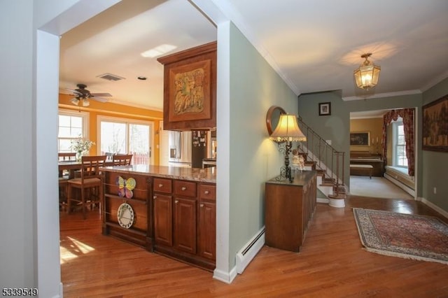 interior space with stairway, light wood-style flooring, a baseboard heating unit, and a wealth of natural light