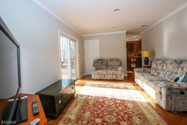 living room with light wood-style floors, visible vents, and ornamental molding