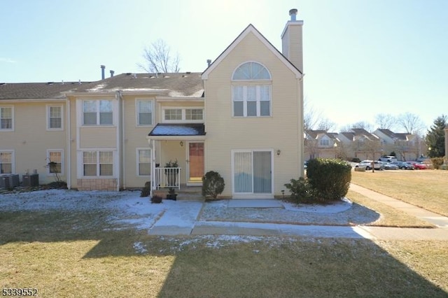 rear view of property with a chimney, cooling unit, and a lawn