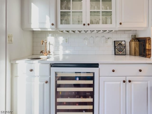 bar with tasteful backsplash, beverage cooler, a sink, and a bar