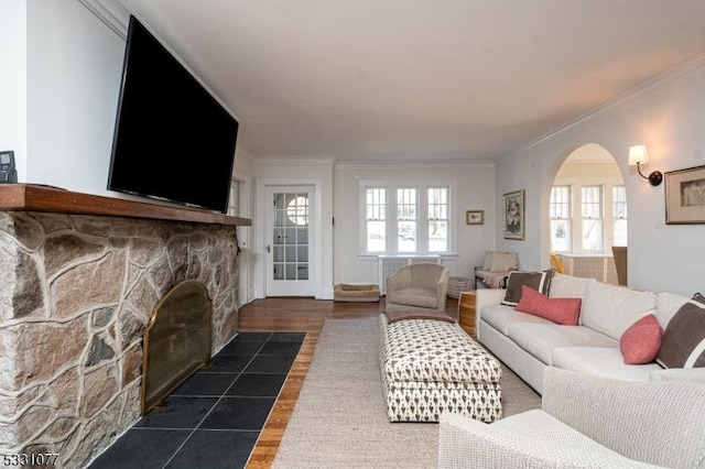 living area with arched walkways, dark wood-type flooring, a fireplace, and crown molding