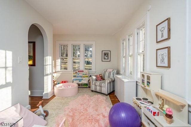 interior space with arched walkways and wood finished floors