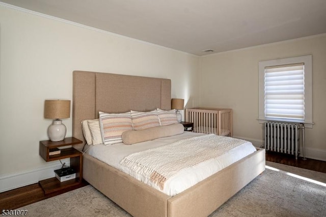 bedroom with radiator, light wood-style flooring, baseboards, and crown molding