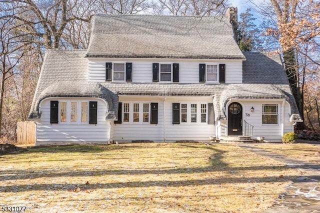 view of front of home featuring a chimney, a front lawn, and roof with shingles